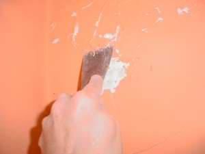 photo scraping away damaged plaster and wall paint