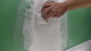 photo wiping sanding dust off a repaired wall crack